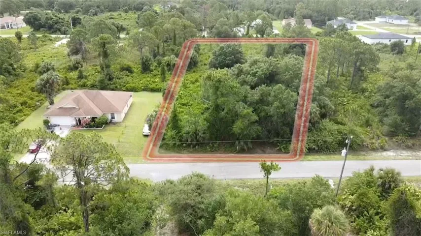 Aerial view of property and surrounding area featuring a forest and property boundaries highlighted