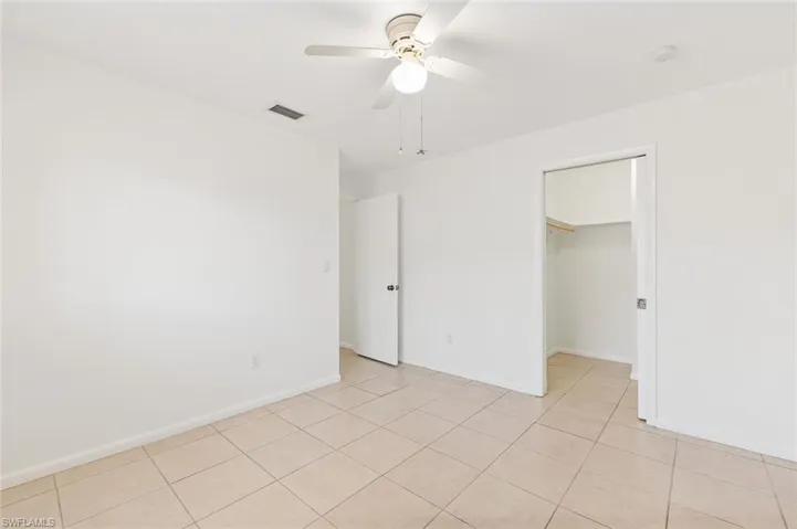 Bedroom two with tile flooring, walk-in closet, and ceiling fan in unit #3.
