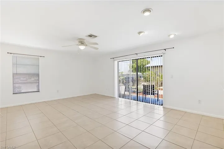 Living room area with tile flooring, ceiling fan, recessed lighting and slider to outside patio area in unit #3.