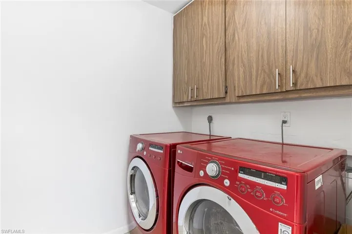 Laundry area with tiled flooring, washer/dryer, and storage cabinets in unit #3.