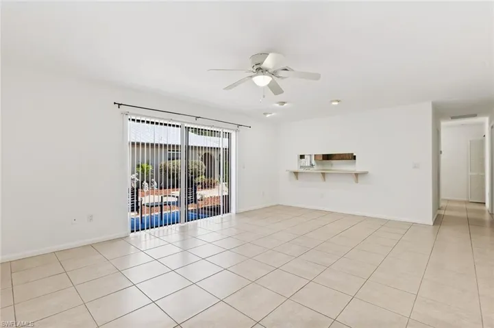 Living room area with tile flooring, ceiling fan, recessed lighting and slider to outside patio area in unit #3