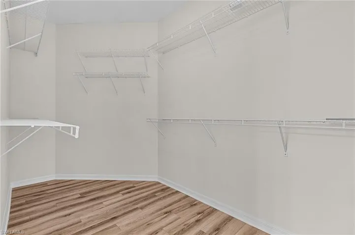 Walk in closet with hardwood / wood-style flooring