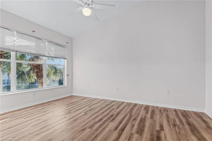 Empty room with ceiling fan, light hardwood / wood-style flooring, and vaulted ceiling