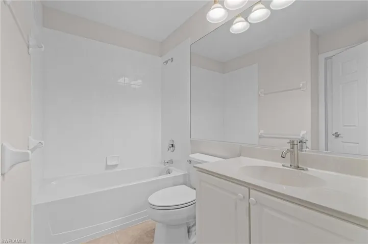 Full bathroom with tile patterned floors, vanity, toilet, and shower / washtub combination
