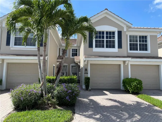 Traditional home featuring an attached garage, stucco siding, and decorative driveway