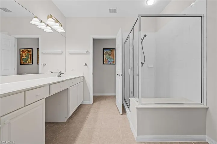 Bathroom featuring vanity, tile patterned floors, and a shower with shower door