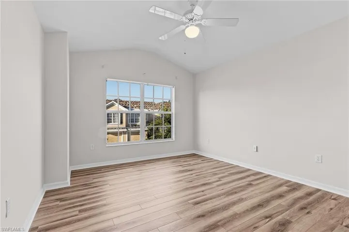 Empty room with light wood-type flooring, ceiling fan, and lofted ceiling