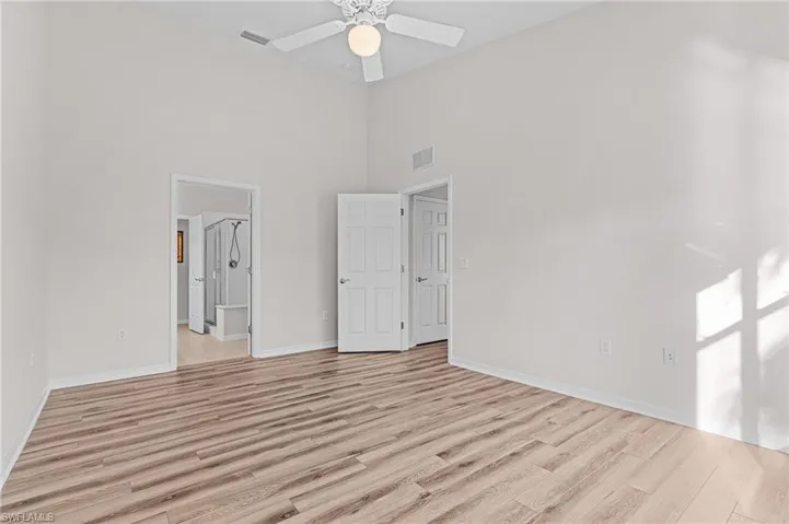 Unfurnished bedroom featuring ceiling fan, light hardwood / wood-style floors, and a high ceiling