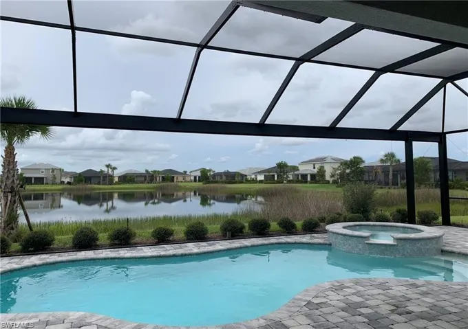 View of swimming pool featuring a water view, a pool with connected hot tub, and a patio area