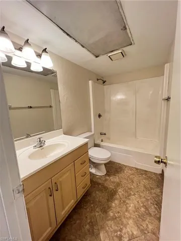 Full bath featuring tub / shower combination, vanity, and a textured wall