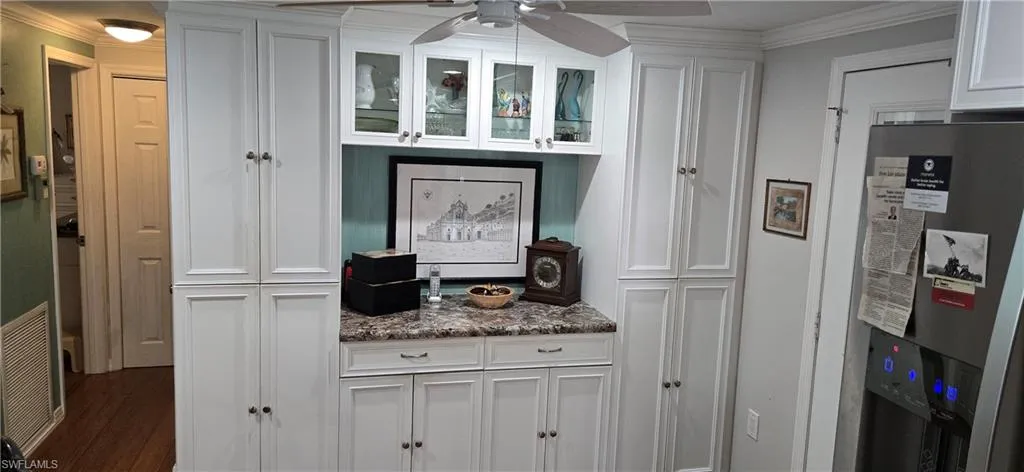 Bar area with freestanding refrigerator, ceiling fan, wood finished floors, and crown molding