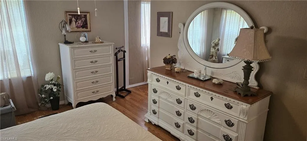 Bedroom with multiple windows and dark wood-style floors