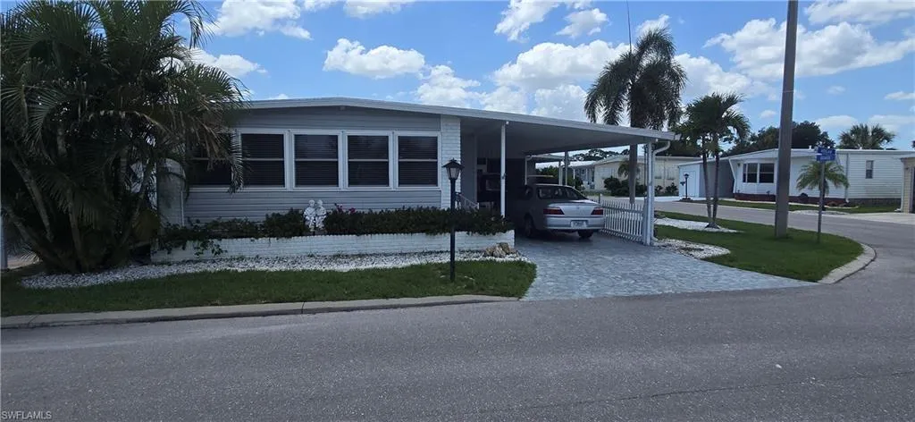 Manufactured / mobile home featuring decorative driveway and a carport