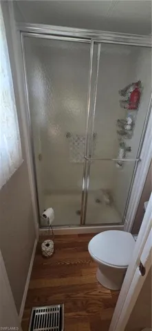 Full bath with wood finished floors and a stall shower