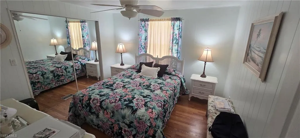 Bedroom with wood finished floors, wood walls, and ceiling fan