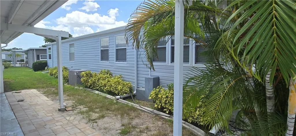 View of side of home with a patio and a lawn