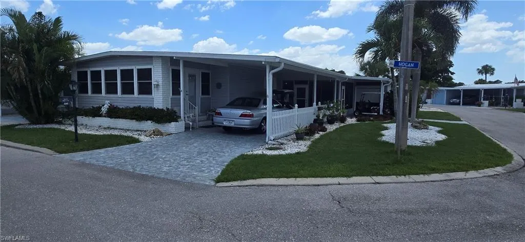 Manufactured / mobile home with decorative driveway, an attached carport, and a front lawn