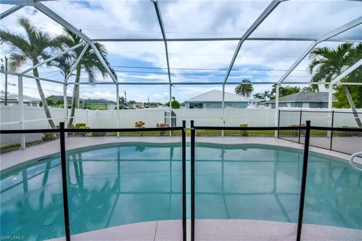 Screened pool enclosure featuring a kidney-shaped pool with integrated steps, surrounded by a textured deck