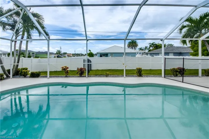 Screened pool enclosure with a free-form pool, surrounding concrete decking, and a privacy fence