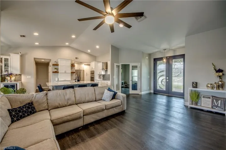 Spacious living area featuring wood-finish flooring, vaulted ceilings with a ceiling fan, and recessed lighting