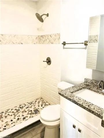Bathroom with vanity, a stall shower, and dark wood-style flooring
