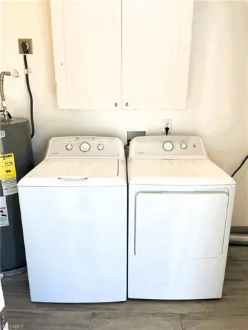 Laundry room featuring wood finish floors, water heater, and washer and dryer