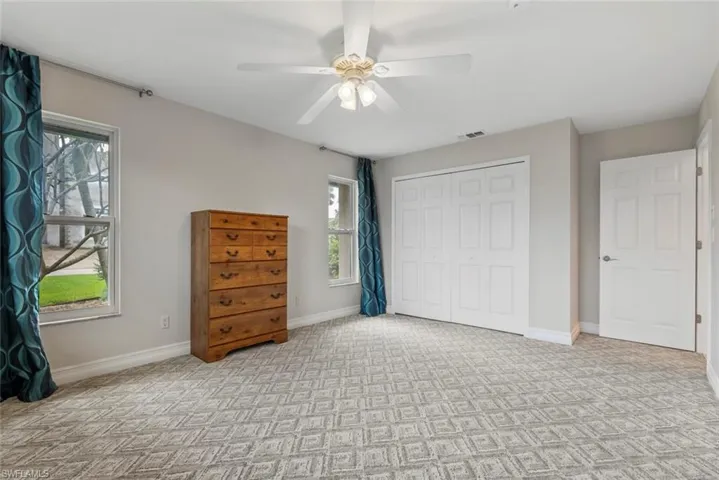 Unfurnished bedroom with ceiling fan, a closet, and multiple windows