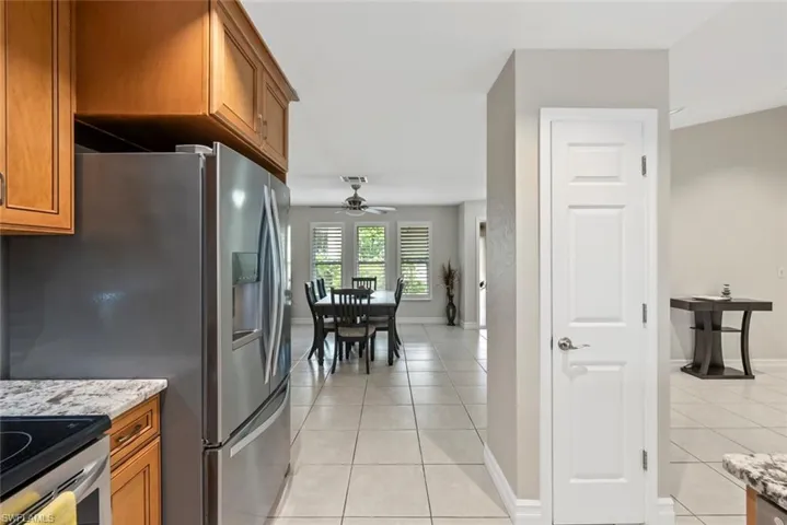 Kitchen with appliances with stainless steel finishes, light stone countertops, ceiling fan, and light tile patterned floors