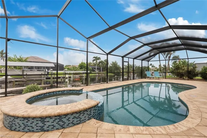 View of pool featuring a water view, a lanai, a patio area, and an in ground hot tub