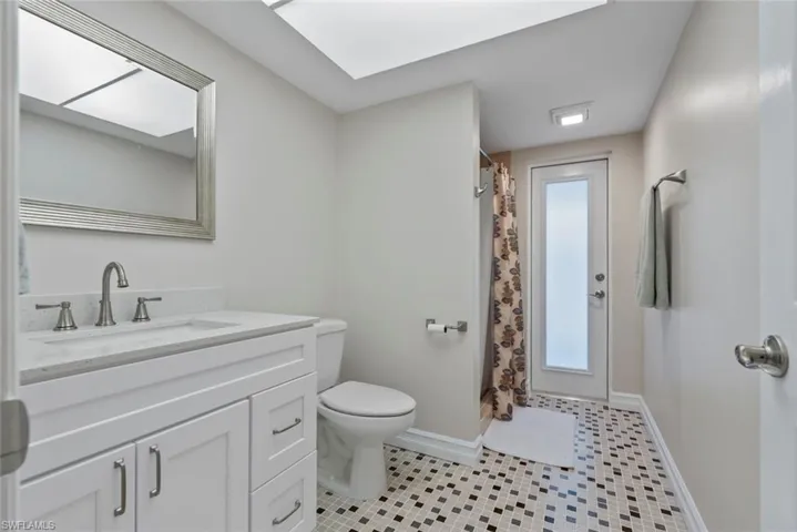 Bathroom with a shower with curtain, vanity, toilet, and tile patterned floors