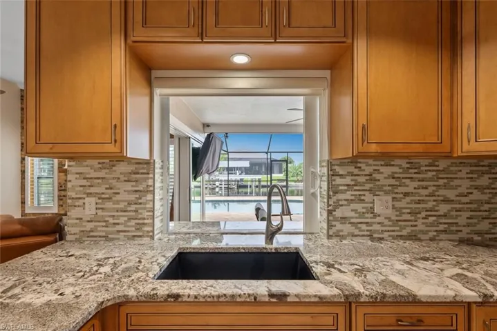 Kitchen with decorative backsplash, sink, and light stone countertops