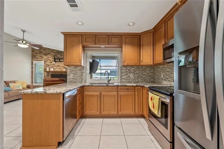 Kitchen featuring light tile patterned floors, sink, kitchen peninsula, stainless steel appliances, and vaulted ceiling