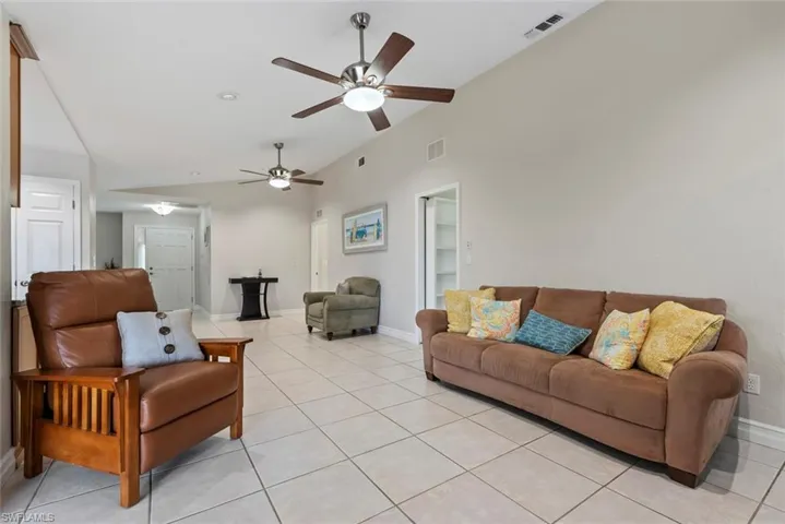 Living room with ceiling fan, lofted ceiling, and light tile patterned floors