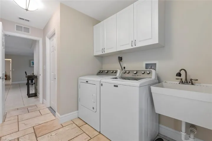 Laundry area featuring sink, washing machine and clothes dryer, and cabinets