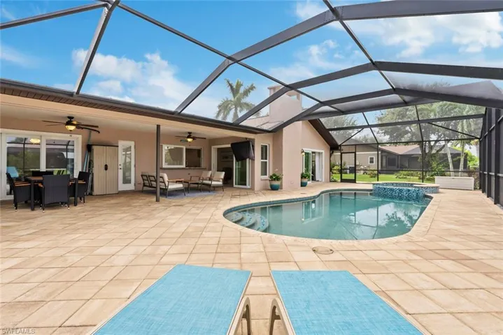 View of pool featuring glass enclosure, ceiling fan, and a patio area