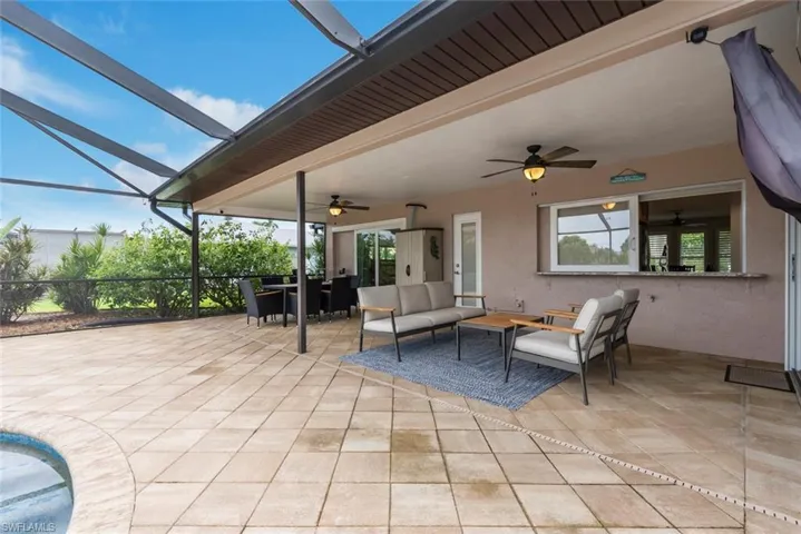 View of patio featuring ceiling fan, an outdoor living space, and glass enclosure