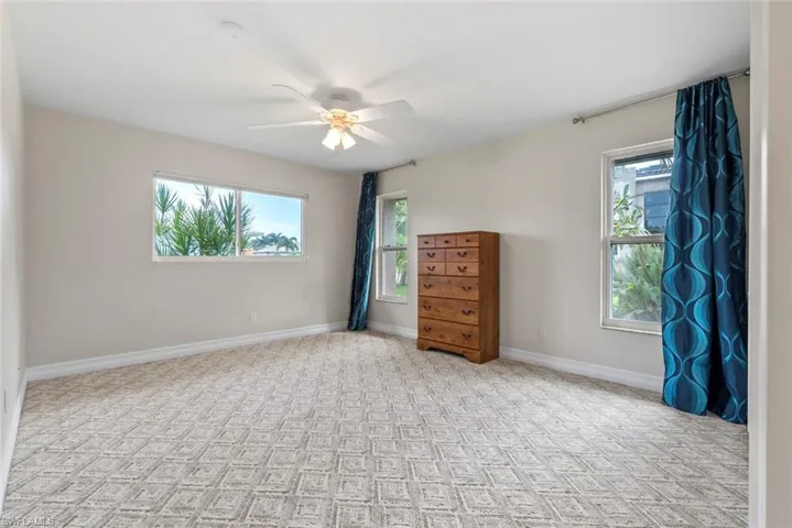 Unfurnished bedroom featuring ceiling fan and multiple windows