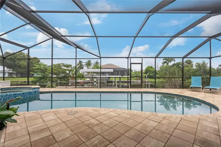 View of pool featuring an in ground hot tub, glass enclosure, and a patio area