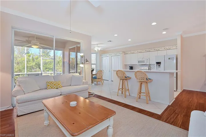 Living area with light wood-style flooring, ornamental molding, and recessed lighting