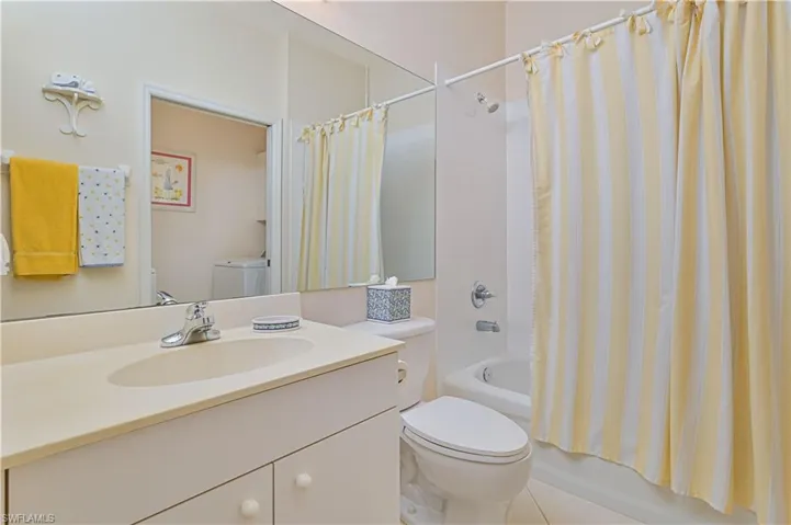 Bathroom with vanity, shower / bath combo, washer / clothes dryer, and light tile patterned floors