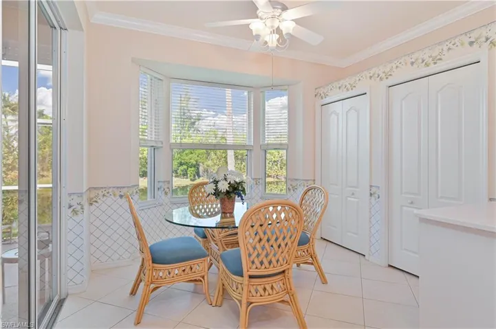 Dining area featuring wainscoting, ceiling fan, wallpapered walls, crown molding, and light tile patterned floors