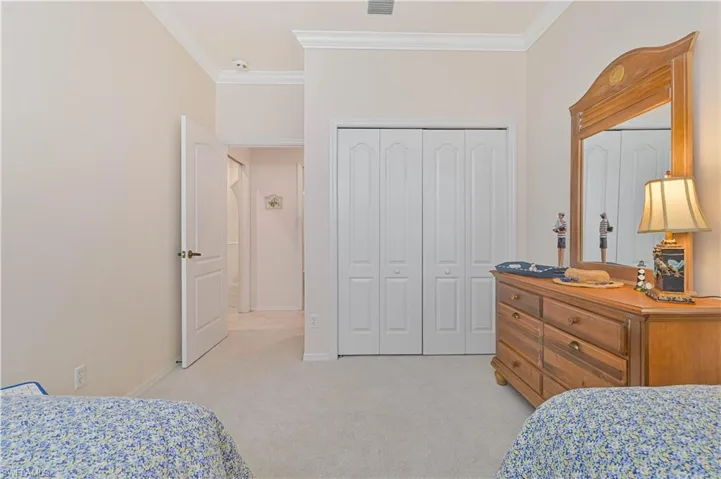 Bedroom featuring ornamental molding, light colored carpet, and a closet