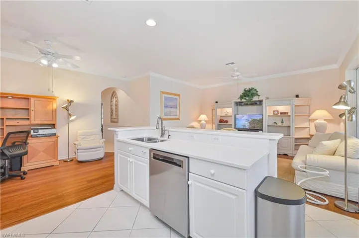 Kitchen with open floor plan, ceiling fan, an island with sink, arched walkways, and dishwasher