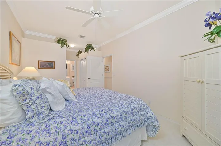 Bedroom featuring ornamental molding, ceiling fan, light colored carpet, and ensuite bath