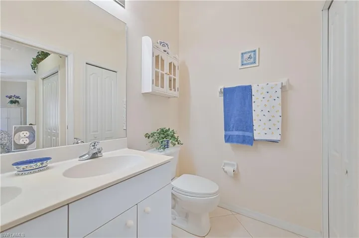 Bathroom with double vanity, light tile patterned flooring, and a closet