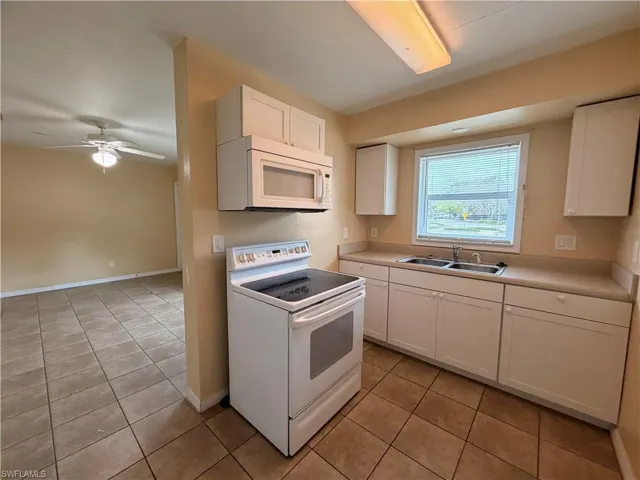 Kitchen with white appliances, white cabinets, light tile patterned floors, and light countertops