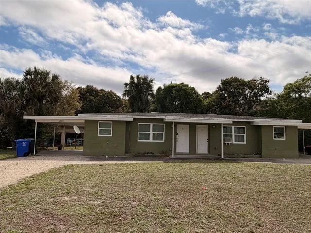 Single story home featuring an attached carport, a front lawn, and driveway