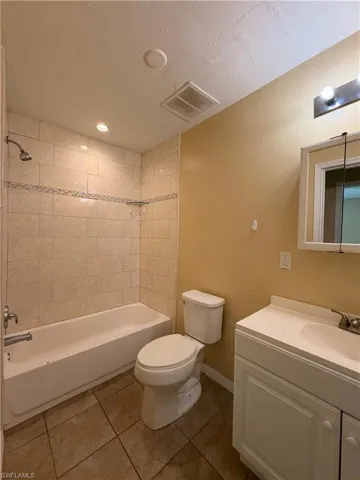 Full bath with vanity,  shower combination, and dark tile patterned flooring