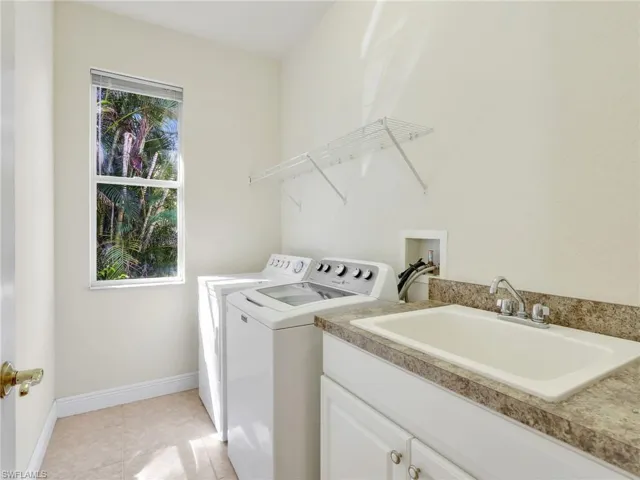 Laundry area featuring independent washer and dryer, light tile patterned floors, and cabinet space