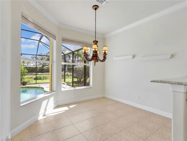 Unfurnished dining area featuring crown molding, a chandelier, light tile patterned floors, and a sunroom